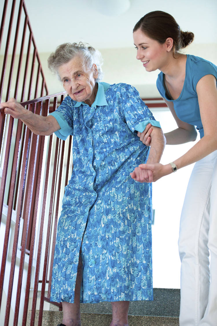 female caregiver helping elderly woman on stairs