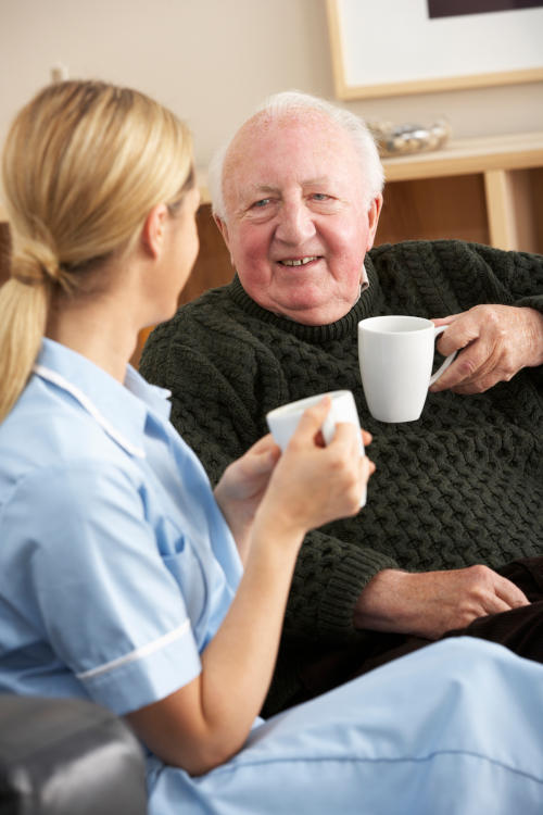 female-careviver-male-senior-having-coffee Caregiver visiting senior man at home